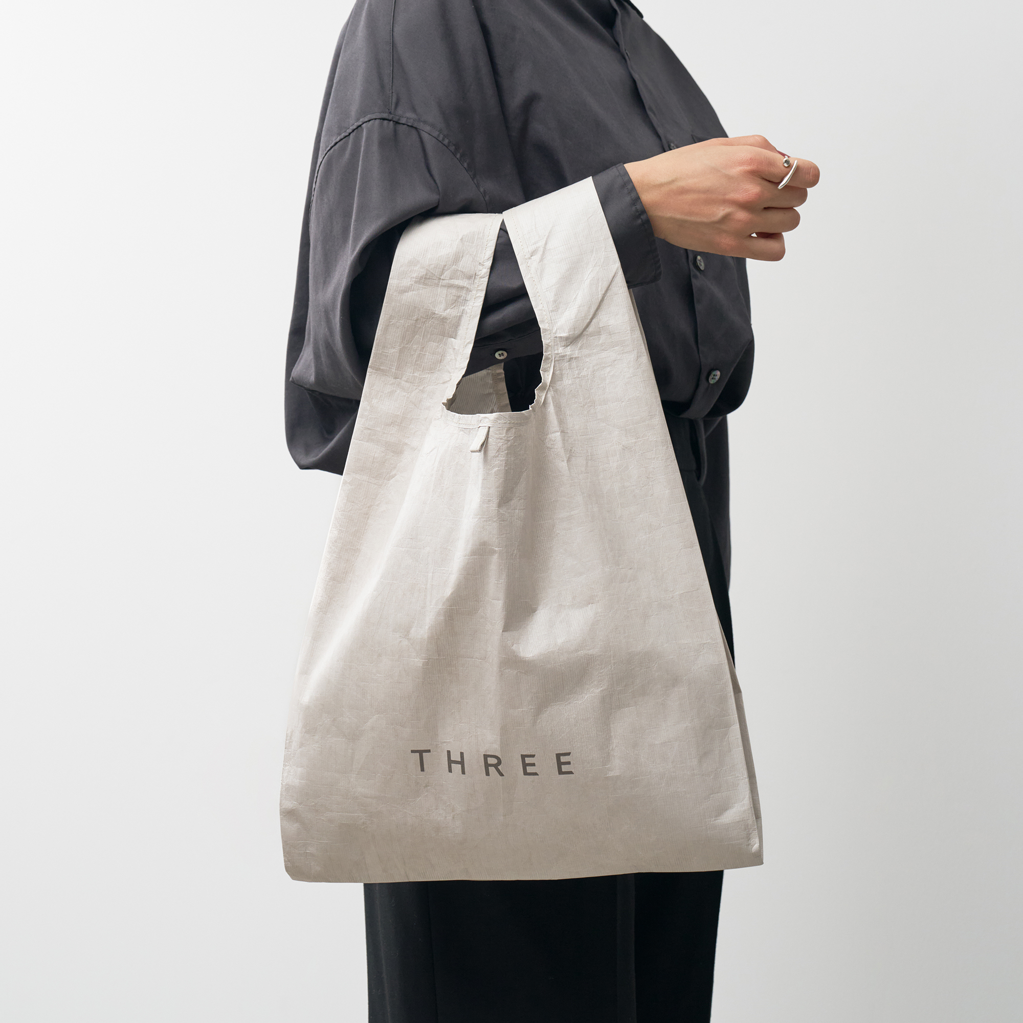 THREE スプリングギフト チャームポーチ&マルシェバッグ バッグを持っている人物